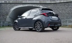 Szary Toyota Yaris Hybrid z czarnym spoilerem i felgami stoi przed tunelem.