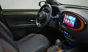Interni moderni della Toyota Aygo X: sedili trapuntati, volante sportivo e un vivace touchscreen centrale con Apple CarPlay.
