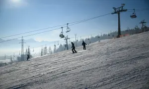 Narciarze i snowboardziści szusują po ośnieżonym stoku, podziwiając piękne widoki. Białka Tatrzańska oferuje wspaniałe atrakcje zimą.