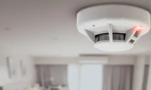Détecteur de fumée blanc au plafond, voyant rouge allumé. Il est temps de changer la pile de ce détecteur de fumée insafe.