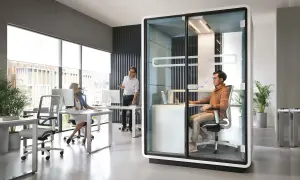 Bureau moderne avec un espace ouvert, une cabine vitrée pour des appels privés et des postes de travail.