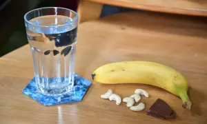 Verre d'eau, banane, noix de cajou et chocolat : idéal pour savoir quoi manger avant de courir le matin.