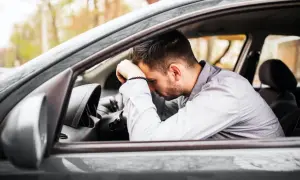 Zabrane prawo jazdy na 3 lata co dalej? Mężczyzna w samochodzie, zrozpaczony, opiera głowę na kierownicy.