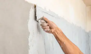 Mano che stende intonaco su un muro, mostrando la differenza tra intonaco kc1 e kd2.