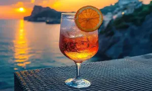 Orzeźwiający drink z pomarańczą na tle zachodzącego słońca nad morzem. Idealny na wakacje, zastanawiasz się crodino co to? To włoski aperitif!