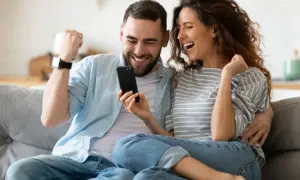 Para jak z liceum, zakochani, cieszą się z sukcesu, patrząc na telefon.