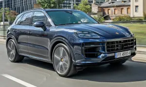 Ciemnoniebieski Porsche Cayenne jedzie po mieście. Sprawdź aktualną porsche cayenne cena.
