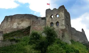 Zamek Czorsztyn, majestatyczne ruiny na wzgórzu, dumnie prezentuje polską flagę na tle błękitnego nieba.