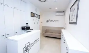 Nowoczesne wnętrze recepcji gabinetu stomatologicznego z kanapą i logotypem.