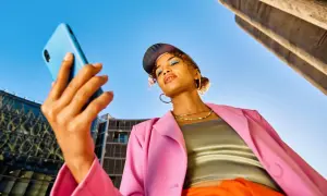Junge Frau mit Handy in der Hand, blickt nachdenklich. Ist Influencer ein Beruf? Sie inspiriert mit ihrem Style.