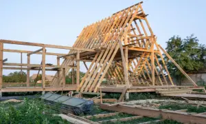 Drewniana konstrukcja domku letniskowego w budowie. Widać szkielet dachu i ścian, a także elementy, które mogą stanowić jaki fundament pod domek letniskowy drewniany.