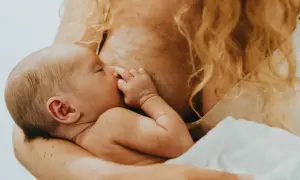 En bebis ammas, med handen vid munnen. En lugn stund för mamma var tredje timme.
