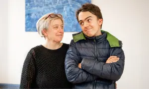 Un sorriso complice tra una donna e un ragazzo autistico, un momento di connessione e comprensione.