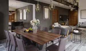 Nowoczesny salon i jadalnia w jednym pokoju. Drewniany stół z krzesłami, w tle szara kanapa i kuchnia.
