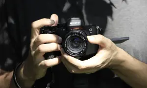 Dłonie trzymające aparat Sony Alpha 7s, gotowe do ustawienia ostrości.