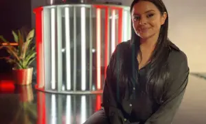 Michelle Kadir ler framför en ljusinstallation med röda och vita rör.