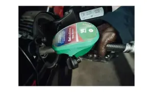 En hand med brun handske håller i en bensinpump med etiketten "GoEasyExtra 98 Bensin E5".