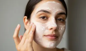 Une femme applique un masque blanc sur son visage, peut-être un soin à l'acide rétinoïque pour le visage.
