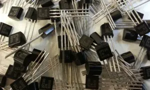 Mnóstwo czarnych tranzystorów 2N3905 z metalowymi nóżkami, gotowych do pracy w układach elektronicznych.
