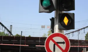 Feux orange clignotant sur un passage à niveau. Le panneau "interdit de tourner à droite" est visible.