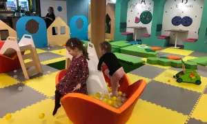 Dwie dziewczynki bawią się w sali zabaw Smart Kids Planet Warszawa. Jedna zjeżdża po zjeżdżalni do basenu z piłeczkami.