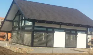 Nowoczesny dom z dużymi oknami dźwiękoszczelnymi, zadaszeniem i żaluzjami.