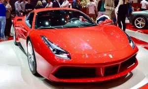 Błyszczący, czerwony Ferrari 488 GTB na wystawie, otoczony ludźmi podziwiającymi jego sportowy design.