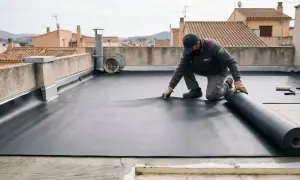 Un trabajador instala una membrana de EPDM, un material sintético de caucho, en una azotea.