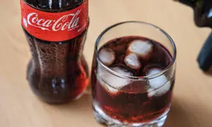 Szklanka z lodem i napojem, obok butelka Coca-Coli. Czerwone wino z colą w szklance, orzeźwiające.