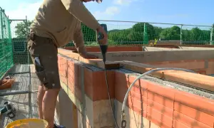Handwerker arbeitet am dachstuhl aufbau. Mit Akkuschrauber werden Holzbalken befestigt.