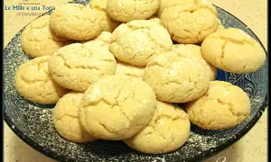 Biscotti con farina di mandorle, dorati e friabili, adagiati su un piatto scuro.