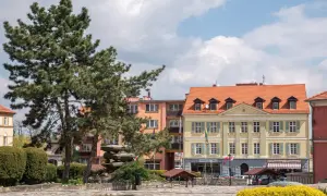 Rynek w Sobótce z kamienną rzeźbą i żółtym budynkiem.