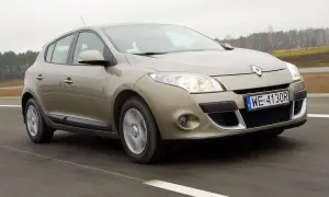 Złoty Megane 3 w ruchu drogowym, z widocznym numerem rejestracyjnym WE 4130R.