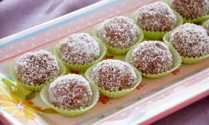 Deliziosi dolci di cocco, palline golose ricoperte di cocco grattugiato, disposte su un vassoio colorato.