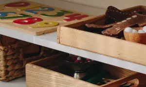 Drewniane pudło na zabawki z pluszowym piernikiem i kuleczkami. Obok puzzle z cyframi i wiklinowy kosz.