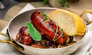 Herzhafte, selbstgemachte Salsiccia mit Rotkohl und Brot in einer Pfanne, garniert mit Salbei und Rosmarin.