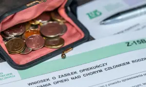 Portmonetka z monetami obok wniosku o zasiłek opiekuńczy. Dokumenty i drobne pieniądze symbolizują wsparcie finansowe dla opiekunów.