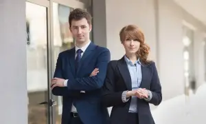 Dwóch profesjonalistów w garniturach stoi przed budynkiem.