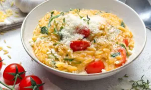 Schüssel mit Orzotto, Tomaten, Spinat und Parmesan, garniert mit Thymian.