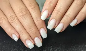 Mains aux ongles blancs laiteux, d'une douceur infinie. Une manucure parfaite pour un look épuré.
