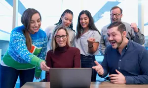 Zespół cieszy się z sukcesu projektu, który jest jak miasto na a. Wszyscy patrzą na ekran laptopa z uśmiechem i entuzjazmem.