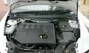 Silnik Volvo V50 2.0D z otwartą maską. Widoczna czarna pokrywa silnika z logo Volvo.