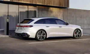 Vit Audi A5 hybrid laddas vid en laddstation. Modern design möter hållbarhet.