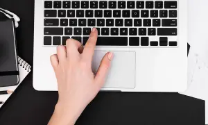 Dłoń naciska klawisz "C" na klawiaturze laptopa, pokazując, jak włączyć klawiaturę.