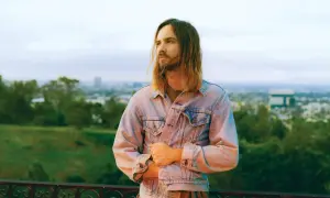 Kevin Parker z Tame Impala Polska w dżinsowej kurtce, z widokiem na miasto.