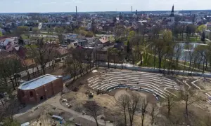 Nowe amfiteatralne trybuny w jarocińskim parku nabierają kształtów. W tle widać panoramę miasta i staw.