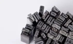 Metalowe czcionki do druku, idealne, by dowiedzieć się, jak zrobić pocztówkę. Litery i cyfry tworzą artystyczny stos.