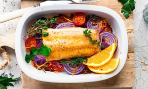 Saftiger Kabeljau im Ofen mit roten Zwiebeln, Tomaten, Kräutern und Orangenscheiben.