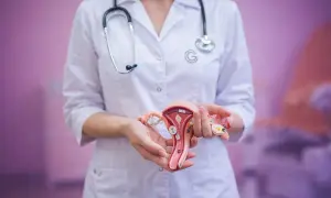 Lekarz prezentuje model narządów rodnych, omawiając zabieg konizacji szyjki macicy.