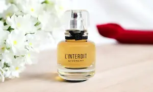 Elegancka butelka Givenchy L'Interdit EDP z białymi kwiatami w tle.